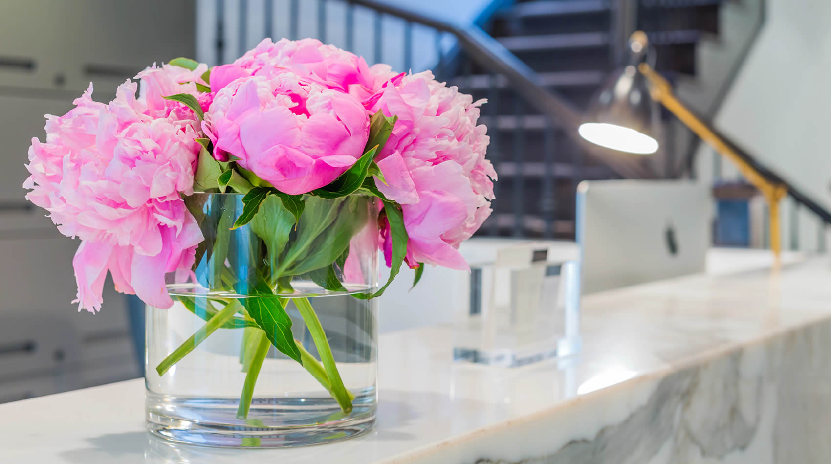 Flors roses i fresques en aigua, decorant la recepció d'un hotel: un toc de frescor per crear una primera impressió encantadora per als hostes.