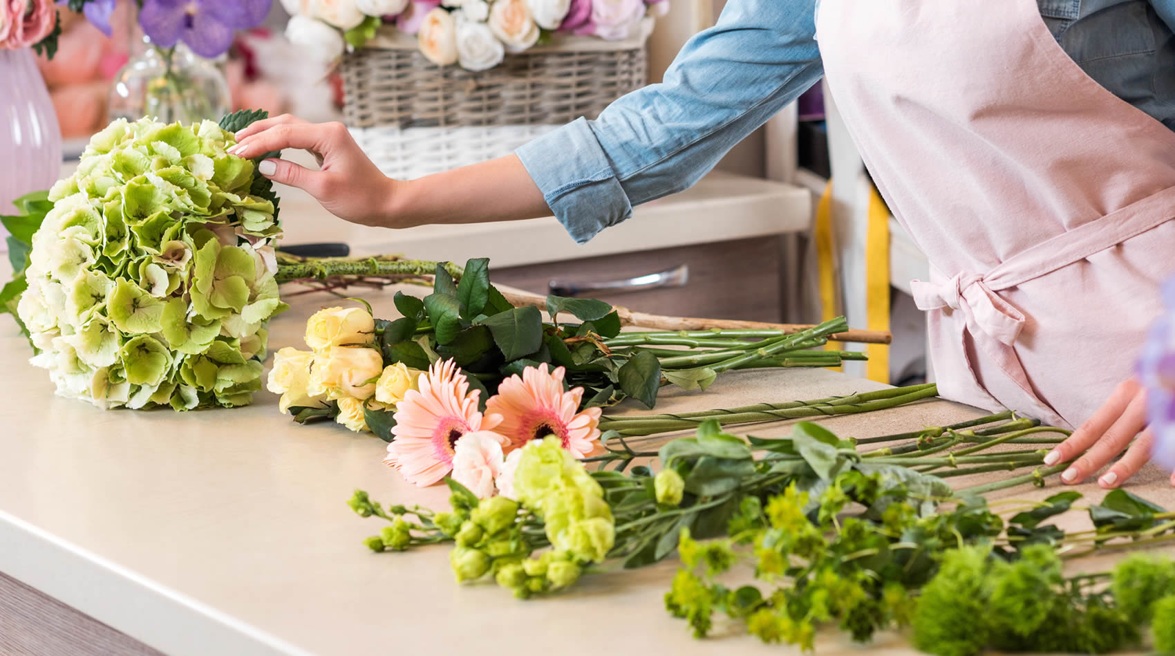 Una florista professional ajuda a triar flors per crear un ram per a una ocasió especial, amb diverses opcions com l'hortènsia verda sobre el mostrador.